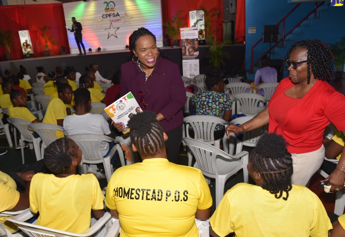 Permanent Secretary in the Ministry of Education and Youth, Dr. Kasan Troupe (left), converses with wards of the State from the Homestead Place of Safety, during the Child Protection and Family Services Agency (CPFSA) talent competition showcasing culinary, visual and performing arts, held at the Chinese Benevolent Association in Kingston, on Thursday (August 29). Sharing the moment is the CPFSA team leader from Manchester, Donna Fuller (right). 