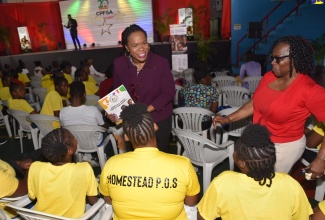 Permanent Secretary in the Ministry of Education and Youth, Dr. Kasan Troupe (left), converses with wards of the State from the Homestead Place of Safety, during the Child Protection and Family Services Agency (CPFSA) talent competition showcasing culinary, visual and performing arts, held at the Chinese Benevolent Association in Kingston, on Thursday (August 29). Sharing the moment is the CPFSA team leader from Manchester, Donna Fuller (right). 