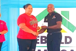 Minister of Labour and Social Security, Hon. Pearnel Charles Jr., presents a grant cheque to St. Elizabeth resident, Maricka Aiken, during the Rebuild Jamaica Initiative handover ceremony, held at the Ministry’s office in Santa Cruz, on Thursday  (August 29). 