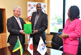 Acting Director General, Office of Disaster Preparedness and Emergency Management (ODPEM), Richard Thompson (centre), presents a gift to President, Japan International Cooperation Agency (JICA), Akihiko Tanaka, during his courtesy call and site visit at ODPEM’s head office on Haining Road in Kingston on Wednesday (July 31). Looking on is Permanent Secretary in the Ministry of Local Government and Community Development, Marsha Henry-Smith. Mr. Tanaka and other JICA officials were updated during the visit on the Improvement of Emergency Communication System Project in Jamaica, a collaborative effort between ODPEM and the Agency.