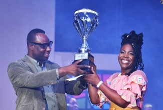 Permanent Secretary in the Ministry of Culture, Gender, Entertainment and Sport, Dean Roy Bernard (left), presents the first-place trophy to winner of the Jamaica Gospel Star Competition, Jaida Messam, at the competition’s finals held on August 4 at the National Indoor Sports Centre in Kingston.
