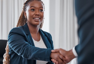 Woman shaking hands with someone in agreement of a partnership.