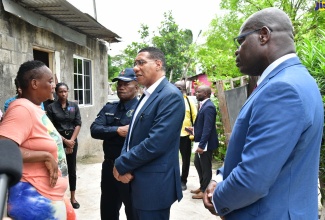 Prime Minister, the Most Hon. Andrew Holness (centre), converses with the mother (left) of one of the eight persons murdered in Cherry Tree Lane, Clarendon, on Sunday night (August 11). He was accompanied by Acting Commissioner of Police, Fitz Bailey (right), and Assistant Commissioner of Police, Calvin Allen. The Prime Minister visited the area on Monday (August 12), where he met with family members and community persons.

