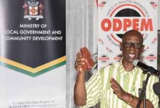 Minister of Local Government and Community Development, Hon. Desmond McKenzie, displays hurricane roof straps while addressing a ceremony on August 26, at the Hugh Lawson Shearer Community Centre in Rocky Point, Clarendon, where the Government commenced its distribution of 10,000 of the straps.

