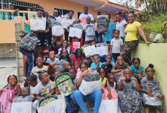 Founder and Head of the Tameka Hill Foundation, Tameka Hill (right), with children at a back-to-school treat, held recently at the Pentecostal City Mission Church Inc, in Mount Ogle, St. Andrew.

