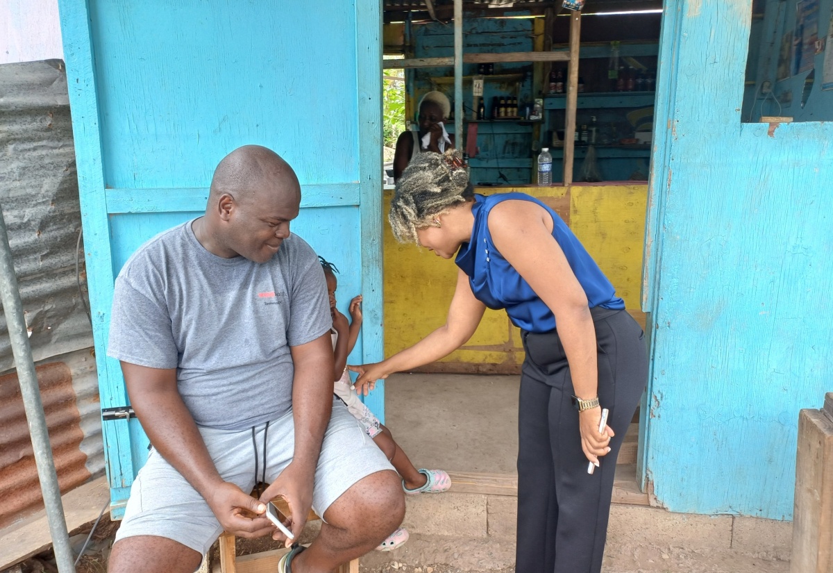 Minister with responsibility for Information, Senator Dr. the Hon. Dana Morris Dixon (right), engages with a child (centre), during a visit to the Cherry Tree Lane community of Clarendon on Monday (August 12).

