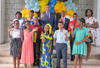 Prime Minister, the Most Hon. Andrew Holness (third left, background) and Permanent Secretary in the Office of the Prime Minister, Ambassador Dr. Rocky Meade (third right, background) with some of the children of employees of the Office of the Prime Minister and the Cabinet Office, who were successful in the Primary Exit Profile (PEP) examinations held earlier this year. The awards function was held at Banquet Hall, Jamaica House, on Thursday (August 29).