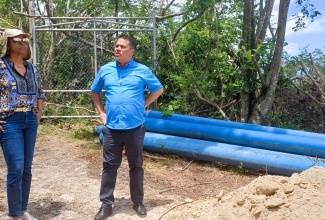 Minister without Portfolio in the Ministry of Economic Growth and Job Creation, Senator the Hon. Matthew Samuda (right), converses with Minister of Legal and Constitutional Affairs and Member of Parliament for St. James West Central, Hon. Marlene Malahoo Forte, during a visit to the site of the National Water Commission's pipe-laying project in Fairfield Irwin, St. James, on Monday (August 19). 

