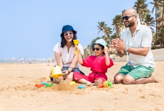 Happy family of three making sand castles on tropical beach. 