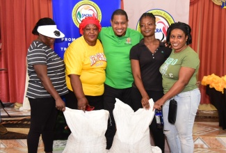 Minister of Agriculture, Fisheries and Mining, Hon. Floyd Green (centre), hands over fertilisers to Buff Bay Valley coffee farmers during a presentation ceremony at the Bangor Ridge Church of God of Prophecy on September 11. The farmers are (from left) Orlando Willis, Norma Howard, Shernette Cobran, and Teneshia Bender.

