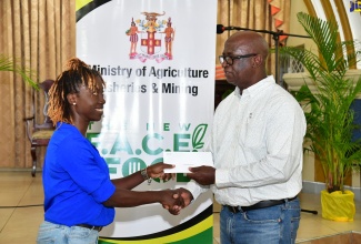 Chief Technical Director in the Ministry of Agriculture, Fisheries and Mining, Orville Palmer (right), presents a voucher for fertiliser to banana farmer Althea McFarlane, during a Hurricane Beryl recovery handover ceremony held by the Banana Board at the Bethel United Church in Highgate, St. Mary, on August 27.

