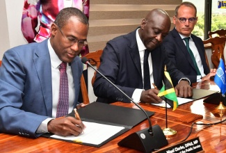 Minister of Finance and the Public Service, Dr. the Hon. Nigel Clarke (left), and Managing Director, International Finance Corporation (IFC), Makhtar Diop (centre), sign the Memorandum of Understanding (MOU), formalising the IFC as Jamaica’s strategic advisor on a portfolio of Public-Private Partnership (PPP) projects. Observing the proceedings is IFC Vice President for Europe, Latin America and the Caribbean, Alfonso García Mora.

