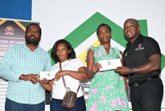 Minister of Labour and Social Security, Hon. Pearnel Charles Jr. (right), is joined by Member of Parliament for Westmoreland Eastern, Daniel Lawrence, in presenting cheques to residents of the parish, Carole Jones (second left) and Camele Campbell, to assist with repairs to their homes, which were damaged during Hurricane Beryl’s passage. The cheques were handed over during a ‘Rebuild Jamaica’ presentation ceremony at The Source in Savanna-la-Mar, on August 29.

