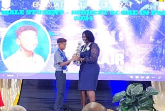 Joel Sinclair receives the award for the male student with the highest score in the 2024 Primary Exit Profile (PEP) from Principal of Mona Preparatory School, Citrine Dixon, at the school’s graduation ceremony held in June.