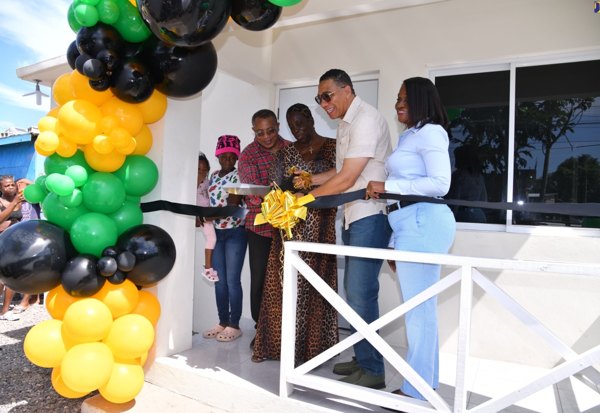 Prime Minister, the Most Hon. Andrew Holness (second right), and Permanent Secretary in the Ministry of Economic Growth and Job Creation, Arlene Williams (right), cut a ribbon during Friday’s (September 6) handover ceremony for a new housing unit at Lot 129 Callaloo Mews, St. Andrew Western, which was developed under the New Social Housing Programme (NSHP). They are joined by Member of Parliament for the constituency, Anthony Hylton (second left), NSHP beneficiary and recipient of the unit, Karen Francis (centre), and her granddaughter, Trishanna Carter (left).

