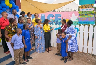 Principal, Swallowfield Primary and Infant School, Jacqueline Bailey (second right), assists Director, Donor and Partnership Management, National Education Trust, Keisha Johnson (third right), in cutting the ribbon symbolising the official handover of a peace garden at the institution, today (September 13). They are joined by stakeholders and children at the institution, located at 11 Whitehall Avenue in St. Andrew. 