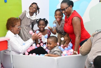 Executive Director of the Early Childhood Commission (ECC), Dr. Karlene DeGrasse-Deslandes (left) and Board Chair of the Digicel Foundation, Joy Clark, play with students in the ball pit in the sensory room, which adjoins the new inclusive classroom at the Salvation Army Arthur Wint Basic School in Lucea, Hanover. The classroom, which is part of the ECC’s Inclusive Legacy Project in collaboration was Digicel Foundation, was officially handed over on September 18.

