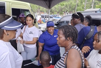 Executive Director, Jamaica Vacations (JAMVAC), Joy Roberts (left), looks on as school supplies are presented to craft traders in Ocho Rios, St. Ann, for their children as part of an assistance initiative spearheaded recently by the Ministry of Tourism and other relevant agencies. The event was held at Ocho Rios Primary School.