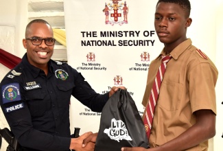 Sergeant Andrew Williams of the Jamaica Constabulary Force (JCF) Community Safety and Security Branch (CSSB), presents grade-11 student at Denham Town High School in Kingston, Kaydon Blair, with a ‘Liv Gud’ branded bag during an interactive session which members of the Ministry of National Security’s ‘Liv Gud’ team had with youngsters at the institution on Friday (September 20).