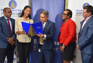 Managing Director (Acting) of the Development Bank of Jamaica (DBJ), David Wan (centre), points out features of a grant document to Sustainability Manager, Esirom Limited,  Khalia Hall (second left) at the DBJ-Boosting Innovation, Growth and Entrepreneurship Ecosystems (BIGEE) Innovation Grant Fund signing ceremony at the DBJ’s offices in Kingston on September 25. Looking on (from left) are Legal Counsel, DBJ, Adrian Nelson; Technical Coordinator of BIGEE, Lu'Shana Cheddesingh; and Chief of Operations at Inter-American Development Bank (IDB), Lorenzo Escondeur.

