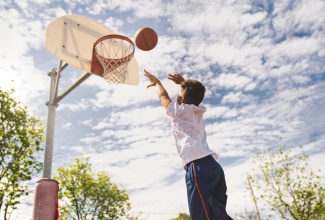 Boy shooting basketball hoops. 