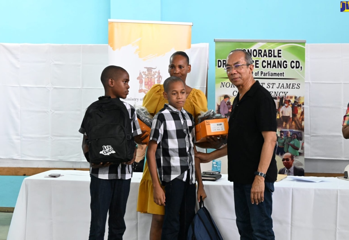 Deputy Prime Minister and Minister of National Security, Hon Dr. Horace Chang (right), participates in a recent handover of back-to-school supplies to students at the Flanker Community Centre in Montego Bay, St. James.

