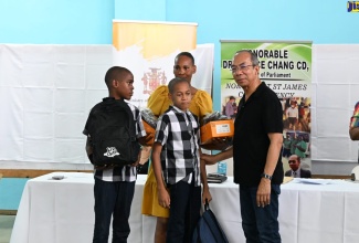 Deputy Prime Minister and Minister of National Security, Hon Dr. Horace Chang (right), participates in a recent handover of back-to-school supplies to students at the Flanker Community Centre in Montego Bay, St. James.

