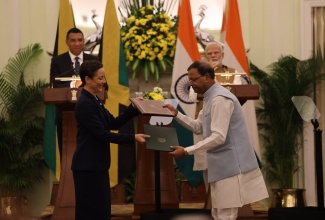 Prime Minister, Dr. the Most. Hon. Andrew Holness (background left) and India's Prime Minister, Shri Narendra Modi (background right),  applaud as Minister of Foreign Affairs and Foreign Trade, Senator the Hon. Kamina Johnson Smith and India’s Minister of State in the Ministry of Finance, Pankaj Choudhary, exchange a Memorandum of Understanding (MOU) aimed at strengthening cooperation between the countries, during a joint press conference in India on Monday (September 30).

